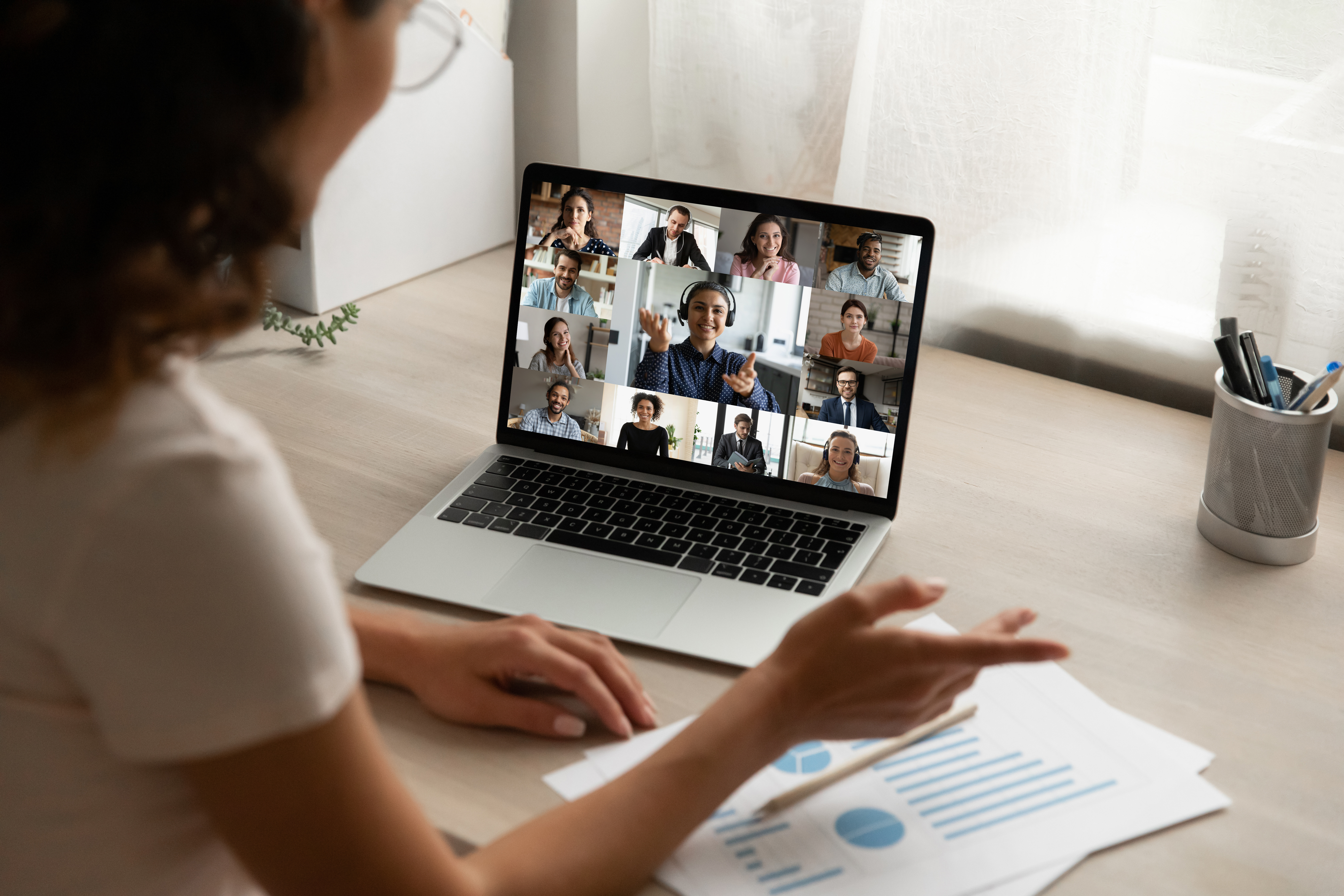 Back view of female employee on video call with colleagues.