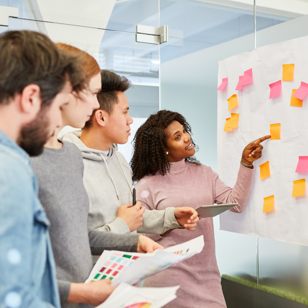 three men and a woman planning together with stickie notes on a wall