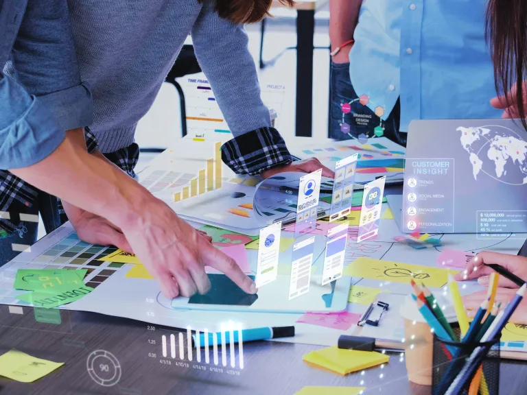 Close up of three people leaning over a table and pointing at meeting materials