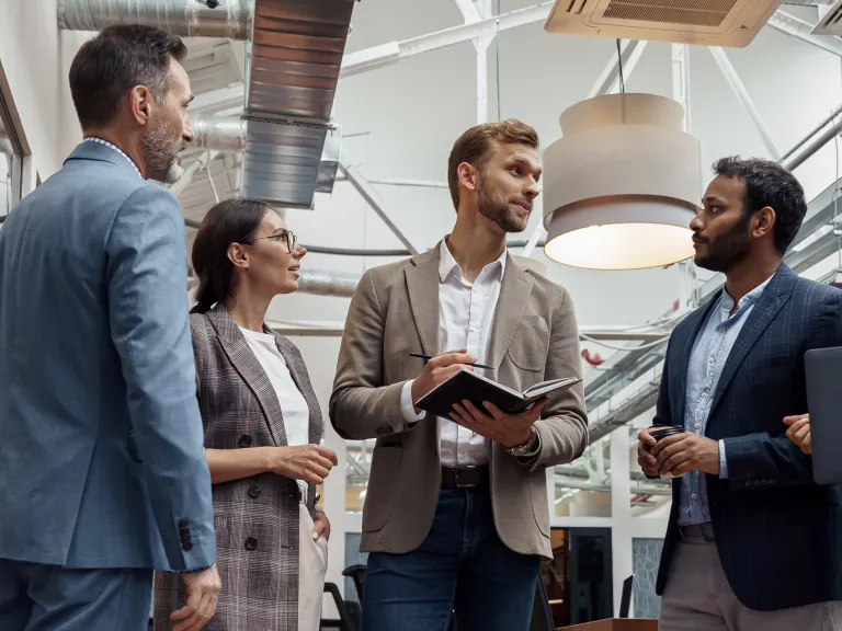 Group of four standing business people discussing in an atrium