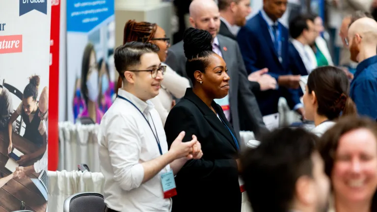 Two people behind their representative table in exhibit hall