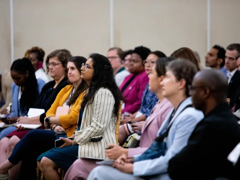 A seated audience listening to a panel out of view